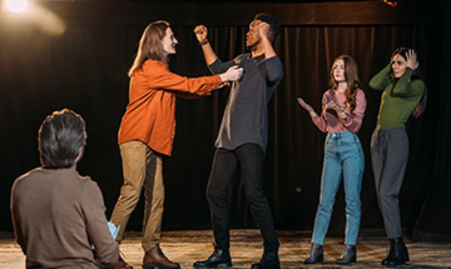 Eine Gruppe von Menschen bei einer Theaterprobe, die gemeinsam Szenen üben.