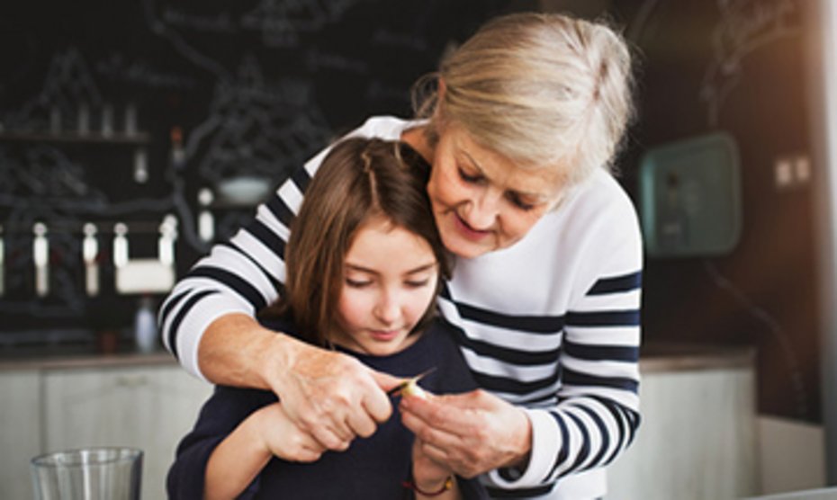 Großmutter schaut Enkelin über die Schulter und hilft bei Handarbeit