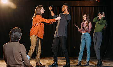 Eine Gruppe von Menschen bei einer Theaterprobe, die gemeinsam Szenen üben.