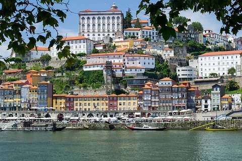 Blick auf die Stadt Porto am Hafen: Historische Gebäude mit bunten Fassaden säumen das Ufer.